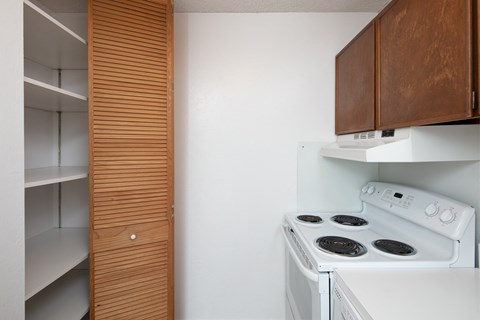 a kitchen with a white stove and a wooden cabinet
