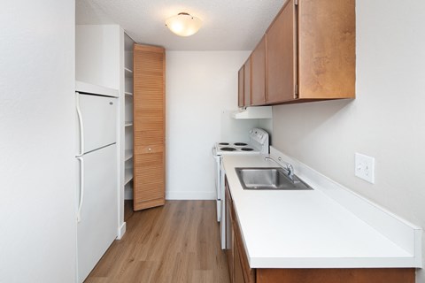 a kitchen with white countertops and wood flooring