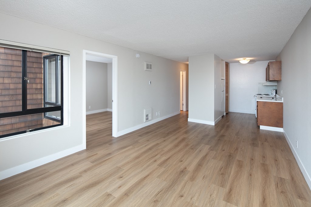 a living room with hardwood floors and a kitchen in the background