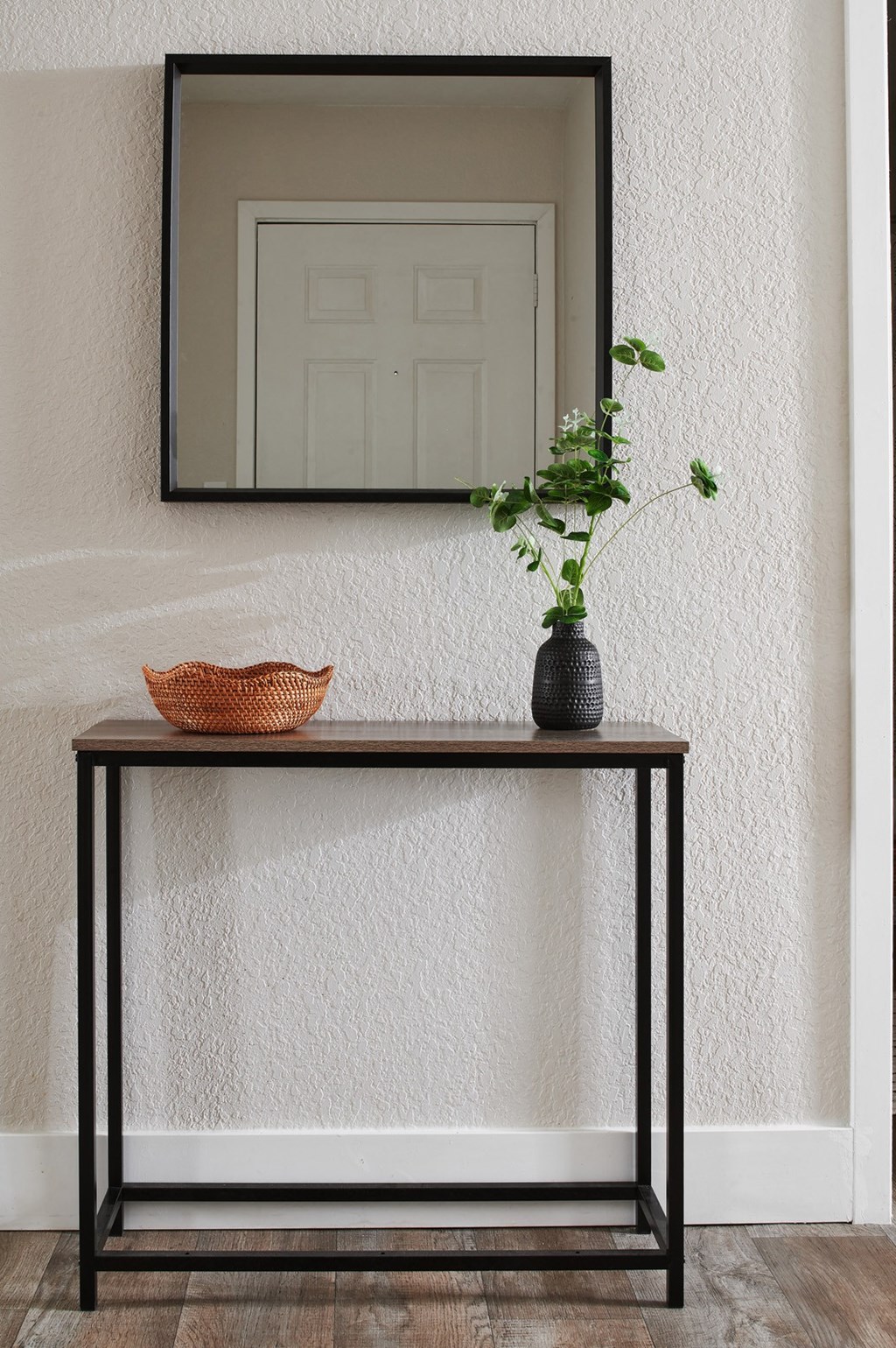 a console table with a vase and bowl on top and a mirror hanging above it
