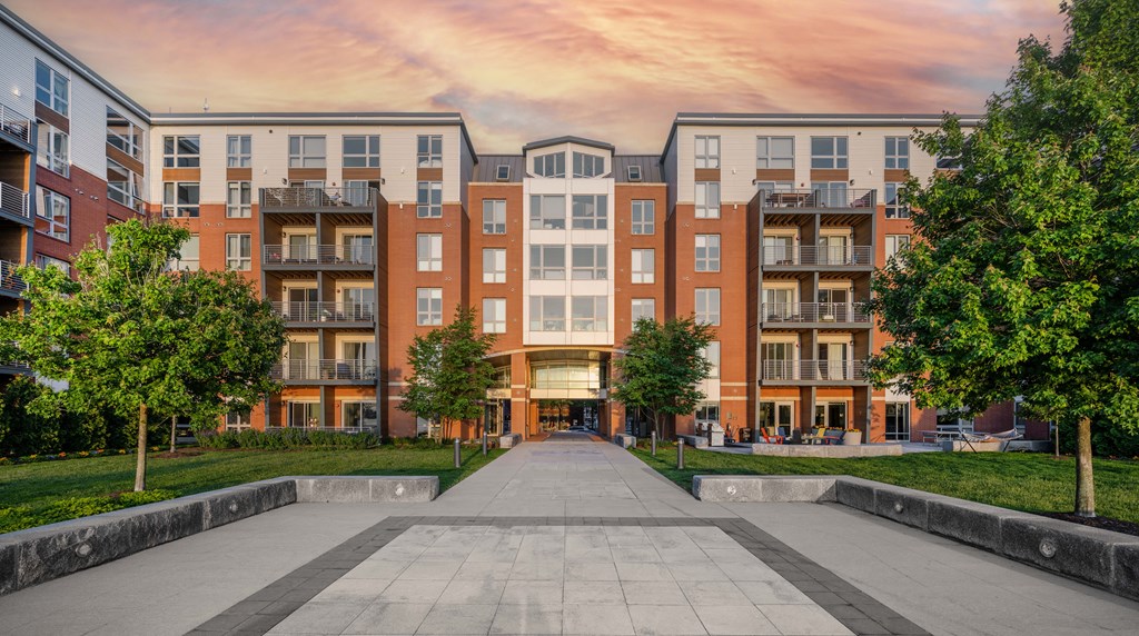 an exterior view of an Boston East Apartments with trees on either side of the walkway