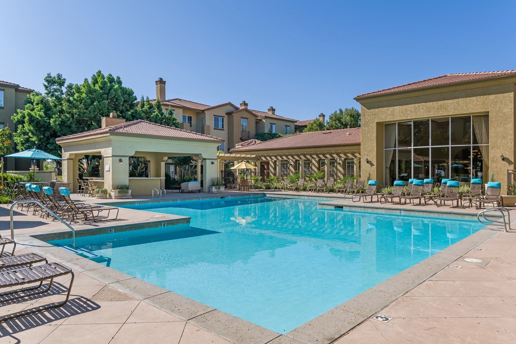 A swimming pool with a sun lounger and a building in the background.