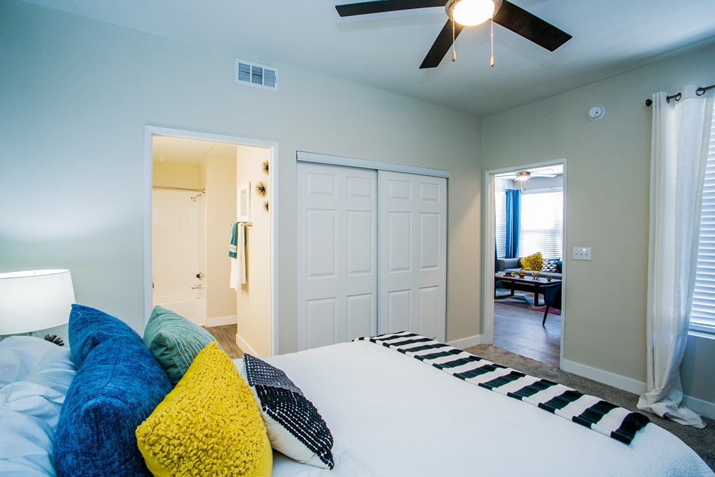 A bedroom with a bed, pillows, and a ceiling fan.