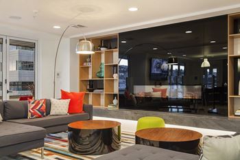 A modern living room with a grey couch, a wooden coffee table, and a large window.