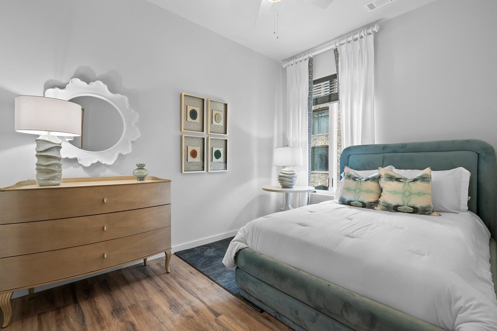 a bedroom with a large bed, a dresser with a mirror on it and a window