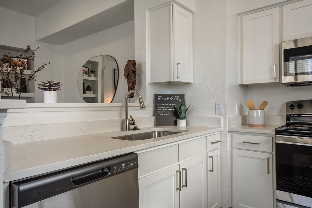 a kitchen with white cabinets and stainless steel appliances and a sink