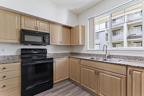 A kitchen with wooden cabinets and black appliances.