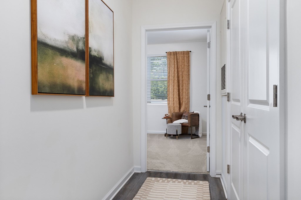 A hallway with a painting on the wall and a closed door on the right.