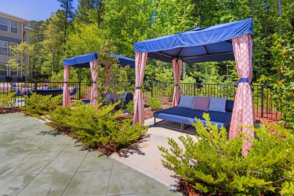 A blue canopy with red curtains is over a bench.