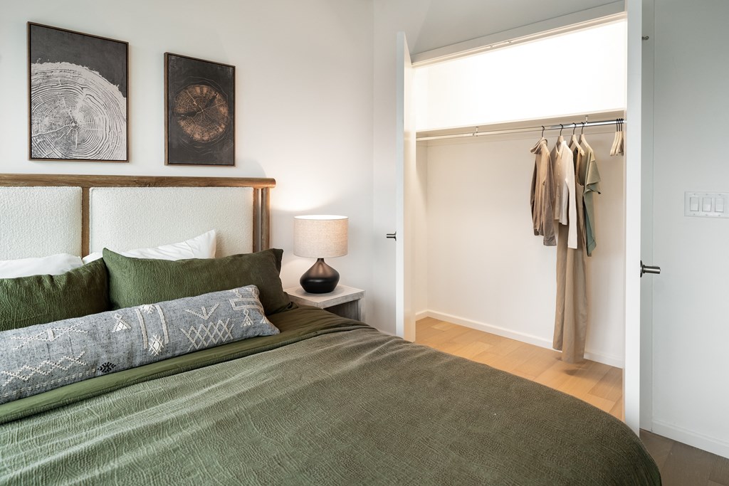 a bedroom with a bed and a closet with clothes hanging on the wall