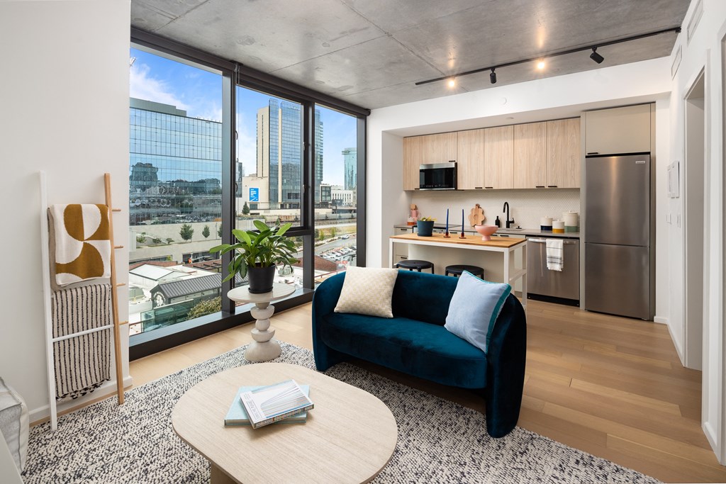 a living room with a blue couch and a kitchen with a city view