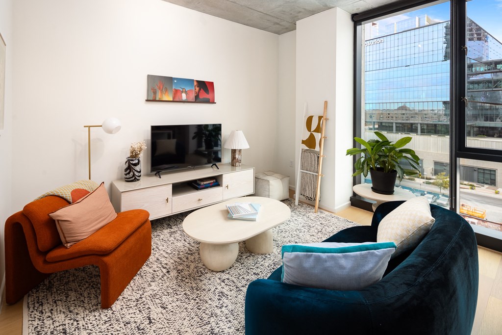 a living room with a large window and a blue couch and chair