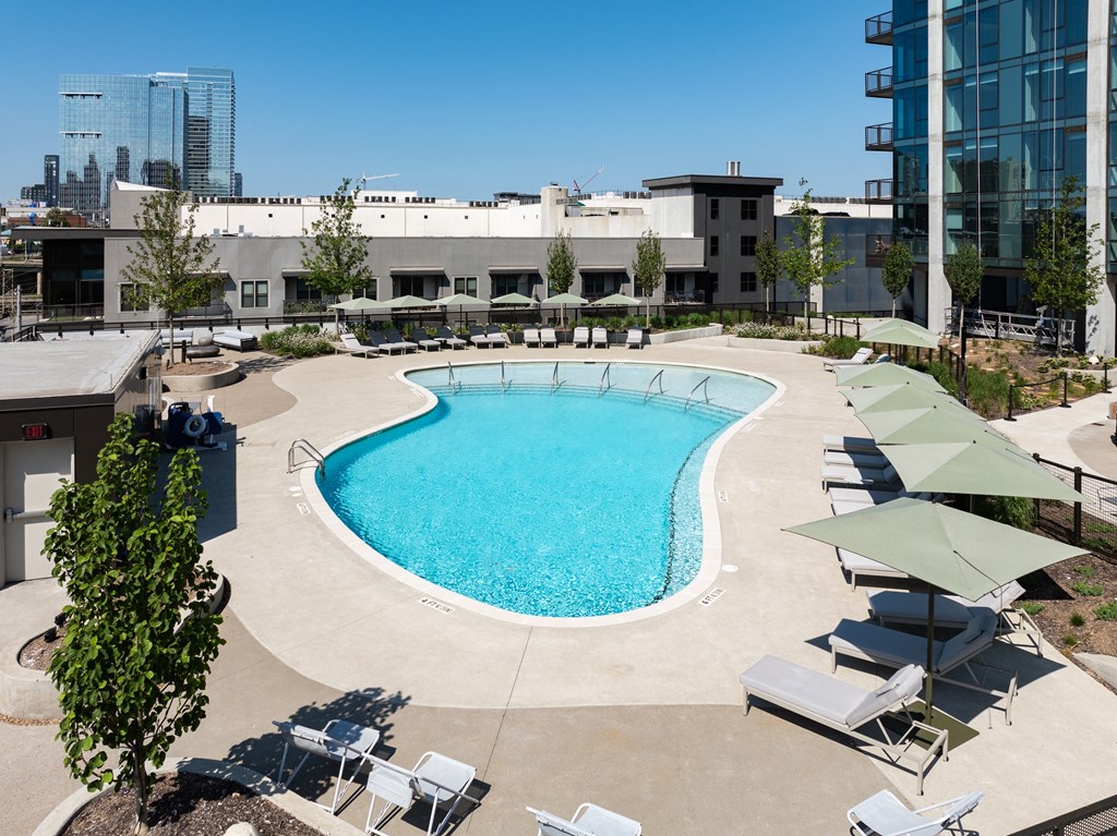 an aerial view of a swimming pool with lounge chairs and a building in the background