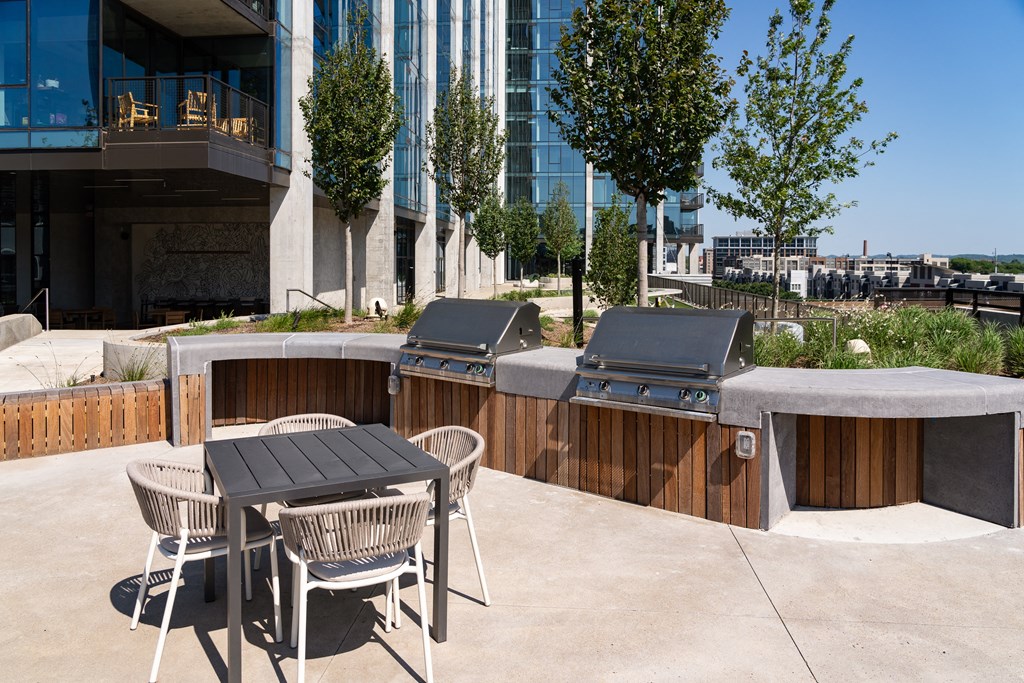 a patio with a table and chairs and two barbecue pits