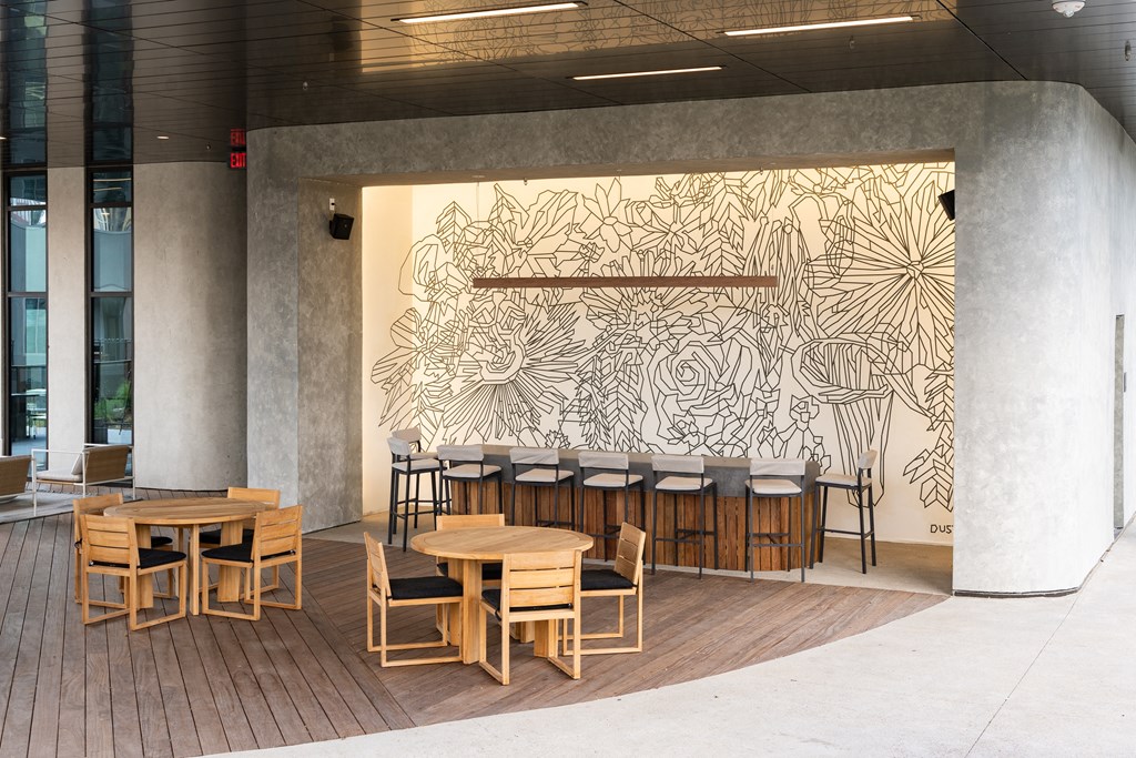 a patio with tables and chairs and a mural on the wall