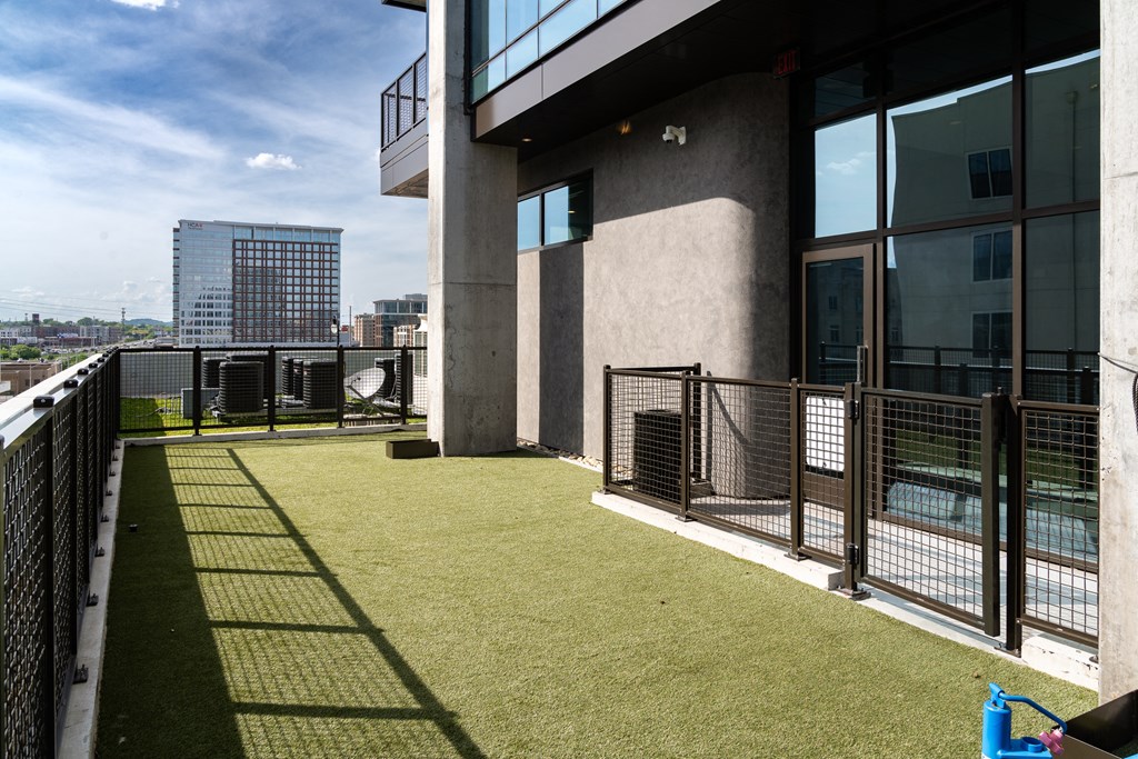 the balcony of a building with green grass and a view of the city