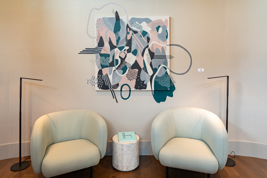 two white chairs in a room with a painting on the wall