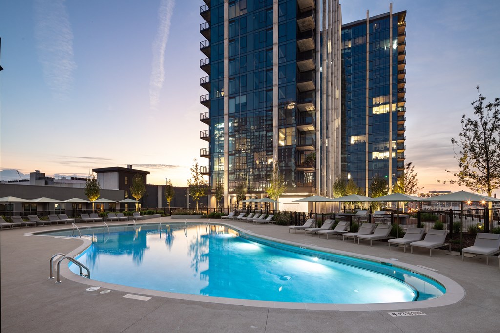 a swimming pool at dusk with a city in the background