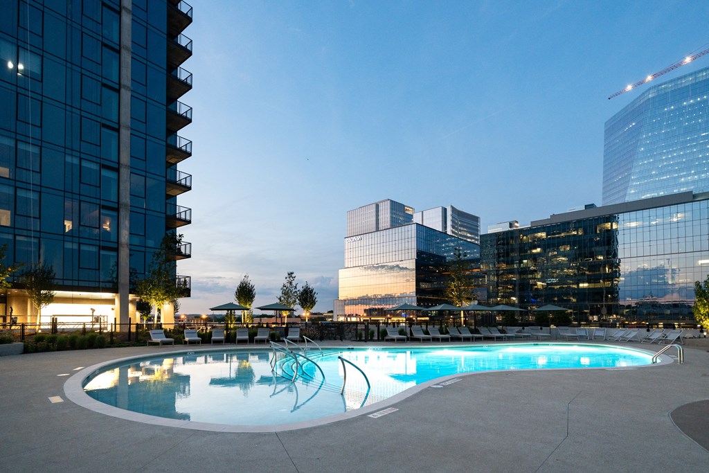 an empty pool at dusk with tall buildings in the background