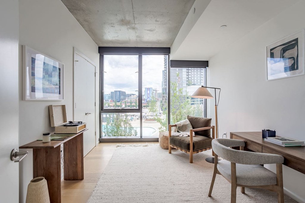 a living room with a chair and a desk and a balcony