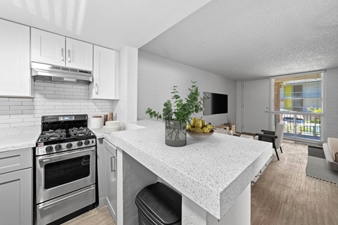 A kitchen with a stove, oven, and a table with a bowl of fruit on it.