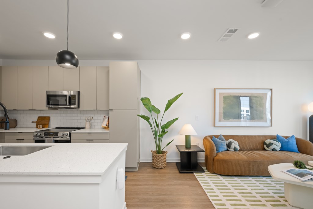 A modern kitchen with a white countertop and a large window in the living room.