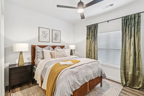 A bedroom with a bed, nightstand, and two framed pictures on the wall.