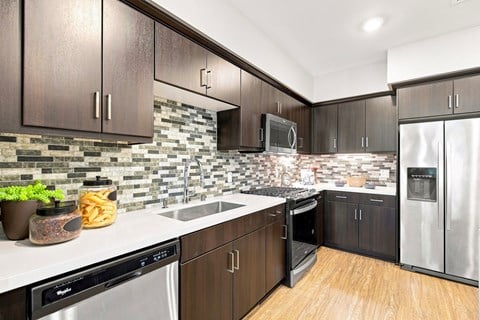 A kitchen with dark brown cabinets and a backsplash of stone tiles.