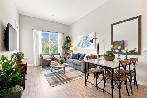 A living room with a grey couch, a wooden table, and a large mirror on the wall.