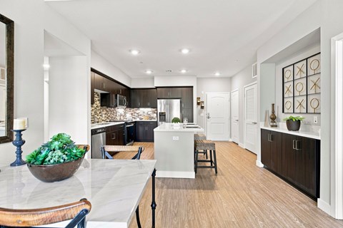 A modern kitchen with a marble countertop and wooden flooring.