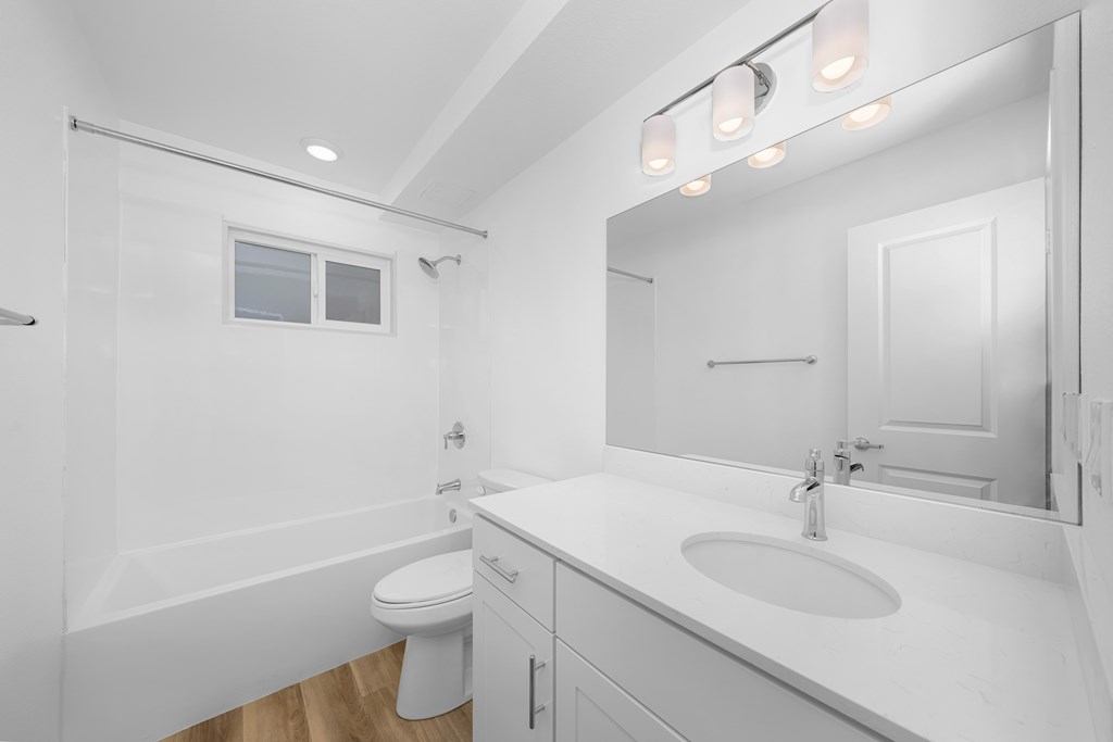 A white bathroom with a toilet, sink, and mirror.