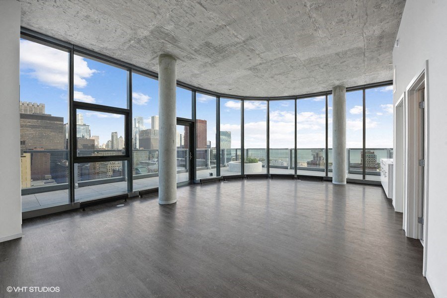 an empty living room with windows and a view of a city