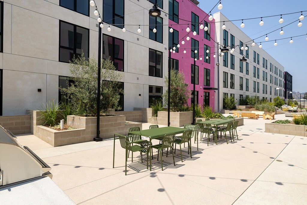 A patio with tables and chairs is surrounded by a building.