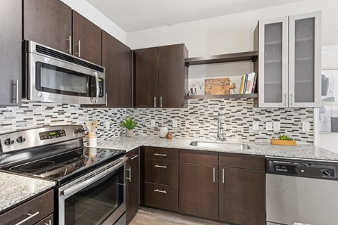 A kitchen with brown cabinets and a black and white tiled backsplash.