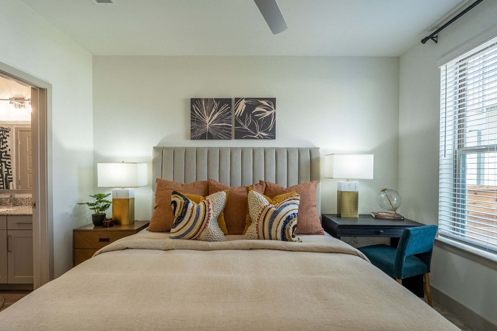 a bedroom with a large bed and a desk with two lamps