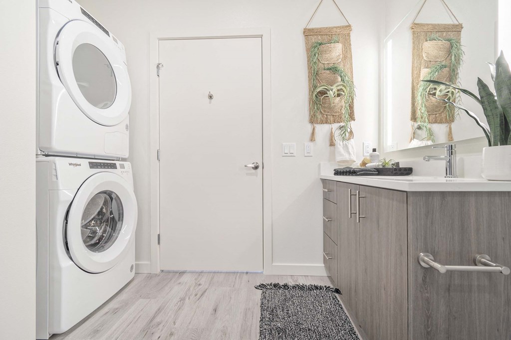 a white laundry room with a washing machine and a sink