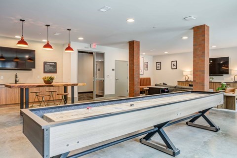A shiny pool table is in the middle of a room with a bar and a TV.