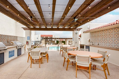 a patio with tables and chairs and a pool in the background