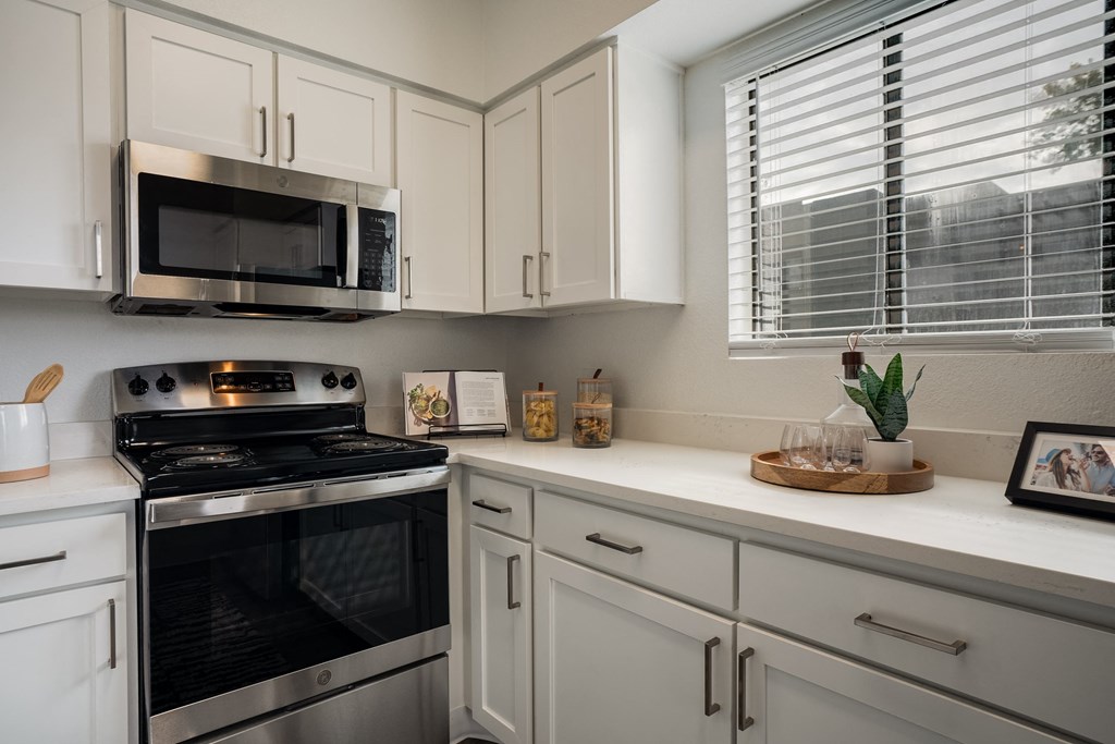 a kitchen with white cabinets and a black oven and microwave