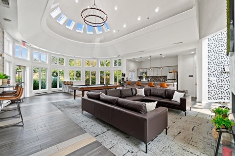 A living room with a brown couch and a chandelier.