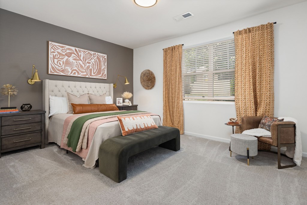 A bedroom with a large bed, a chair, and a window with curtains.