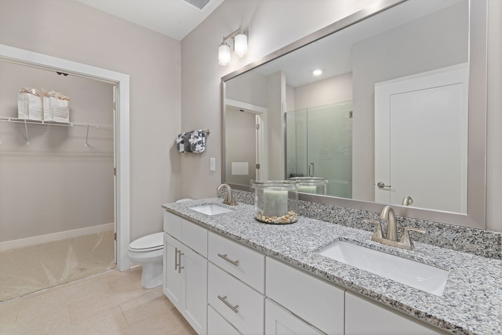 A bathroom with a marble countertop and a large mirror.