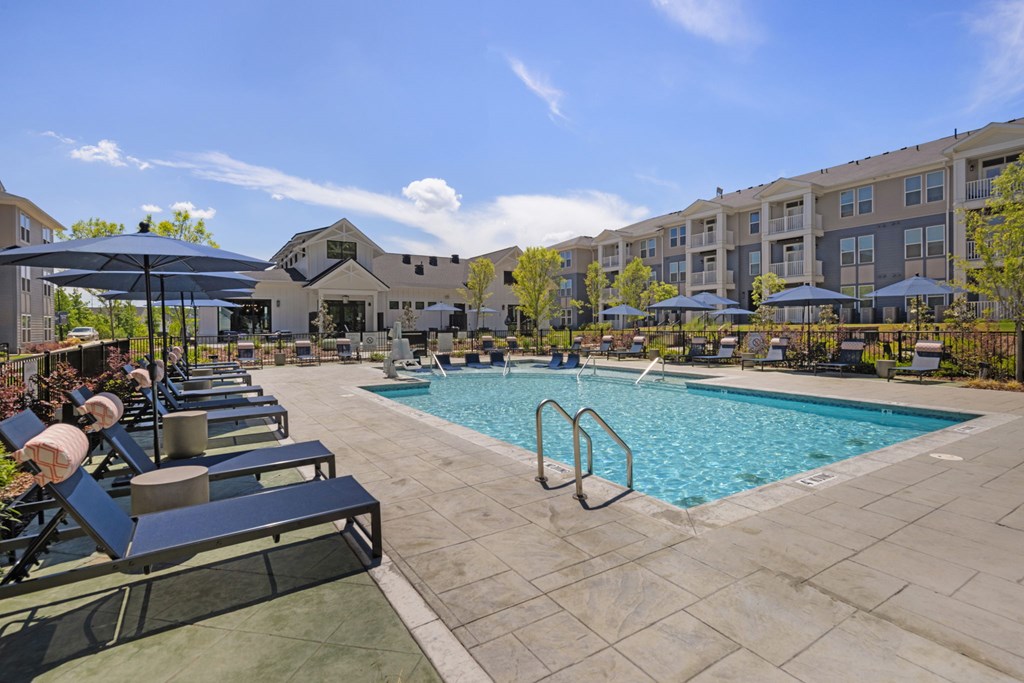 A large swimming pool surrounded by lounge chairs and umbrellas.