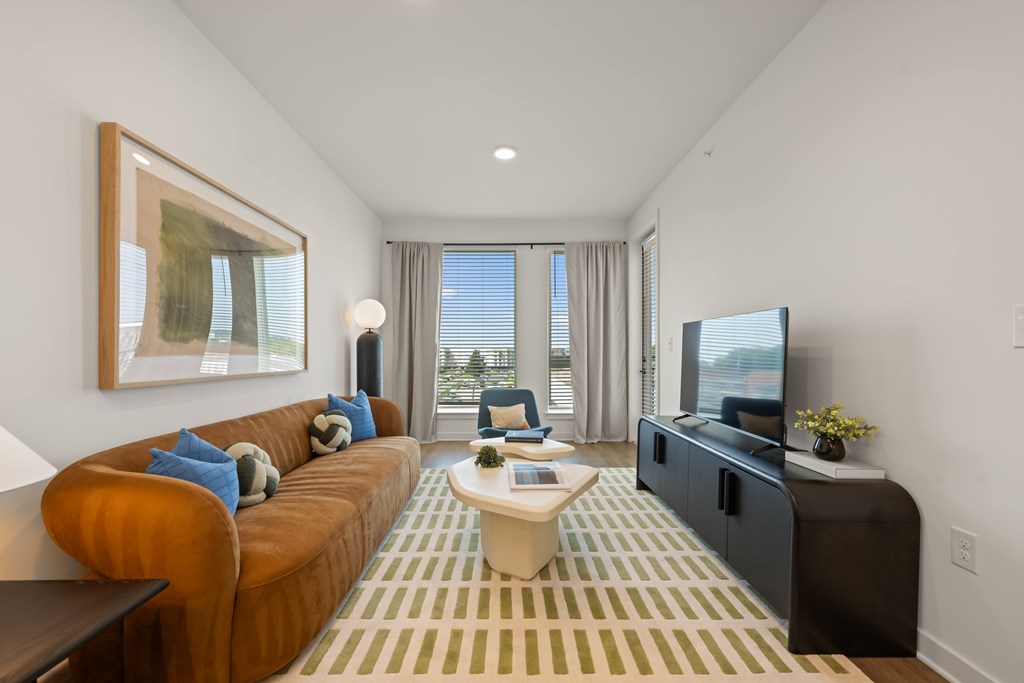 A living room with a brown couch and a painting on the wall.