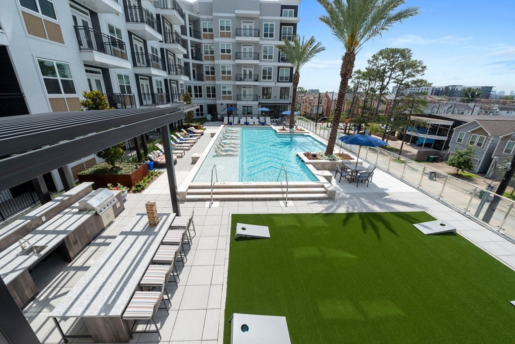 A large swimming pool is surrounded by a grassy area and palm trees.