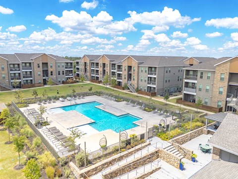 an aerial view of an outdoor pool with apartments in the background