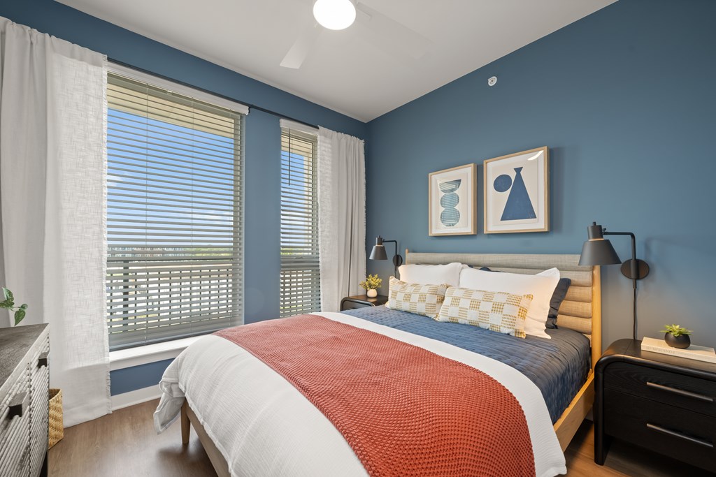 A bedroom with a bed, nightstand, and window with curtains.