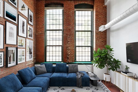 A living room with a blue couch and a brick wall.
