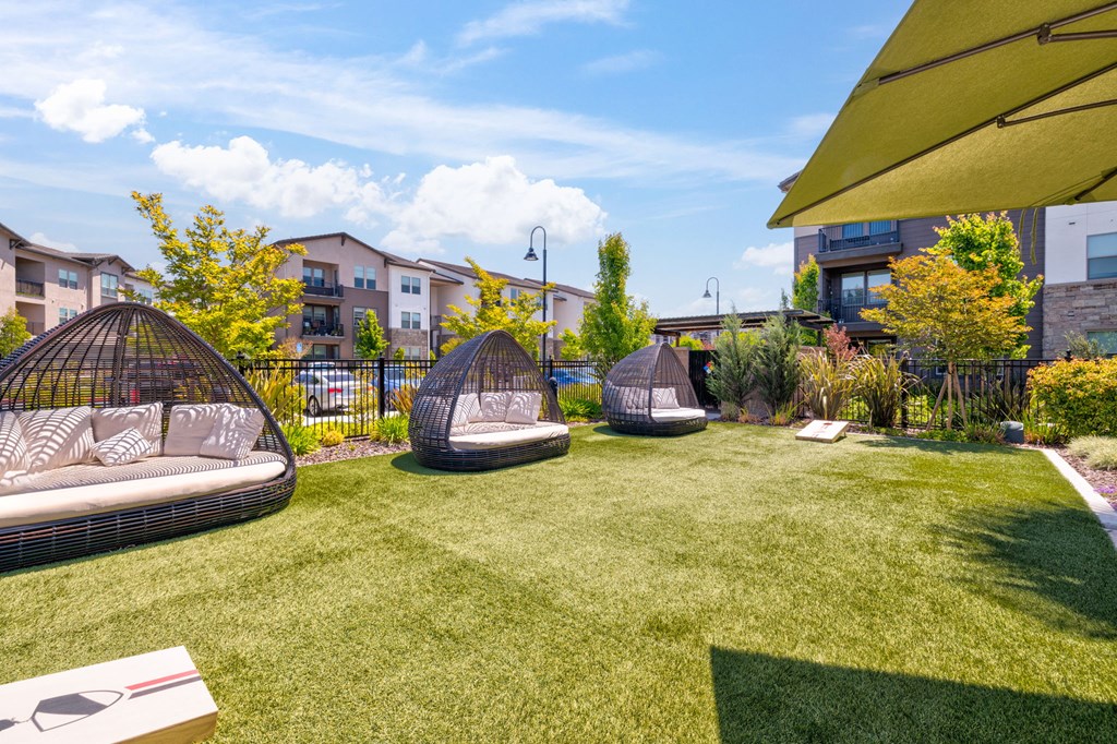 a backyard with lounge chairs and a grassy area with apartment buildings in the background