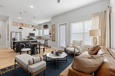A modern living room with a kitchen in the background.